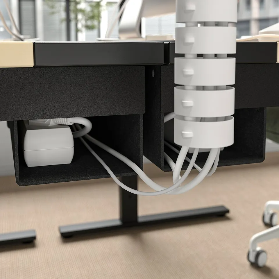 Desk with cable management: white cables organised in tray under black desk.