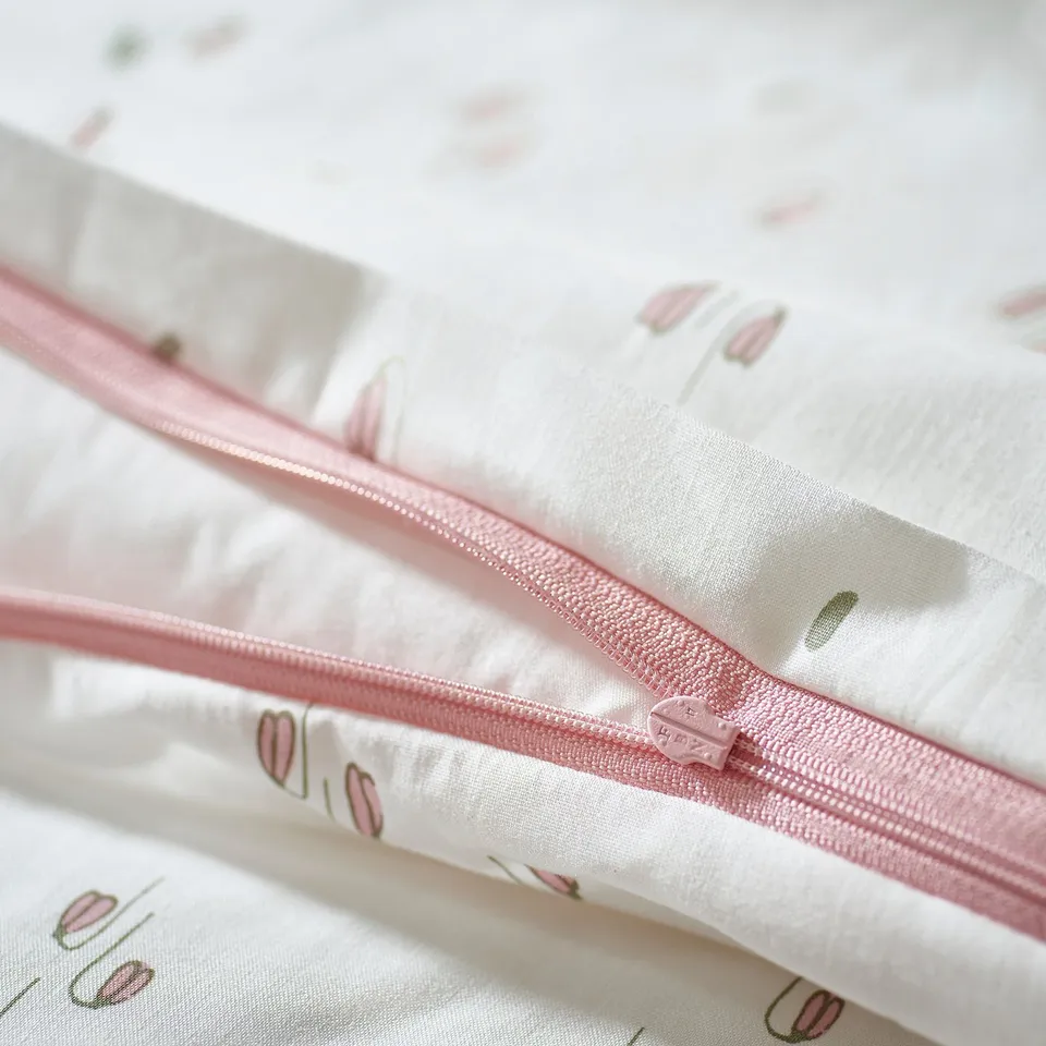 Close-up of pink zip on white duvet cover with pink flowers.