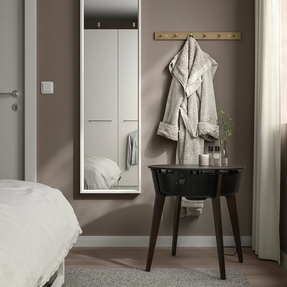 Modern bedroom with STARKVIND air purifier, coat rack, mirrored wardrobe, and bed.