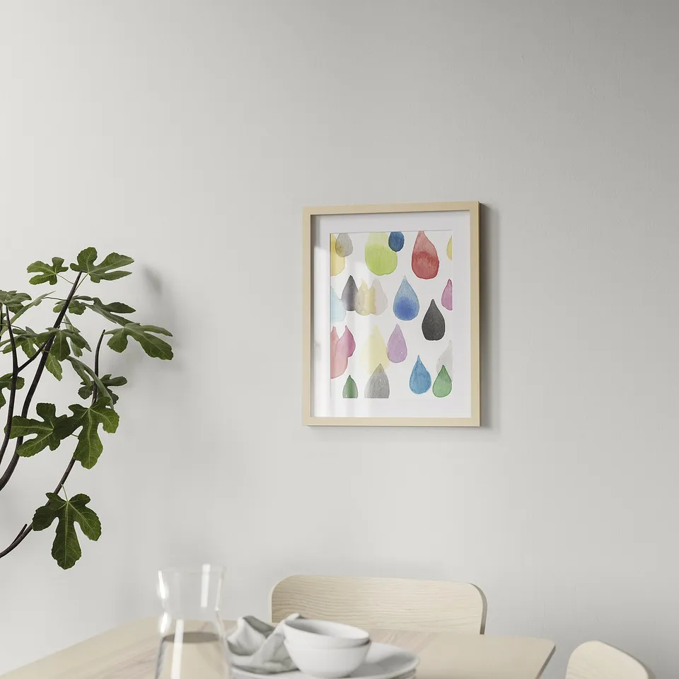 Framed abstract art hangs on a dining room wall, above a wooden table with chairs.