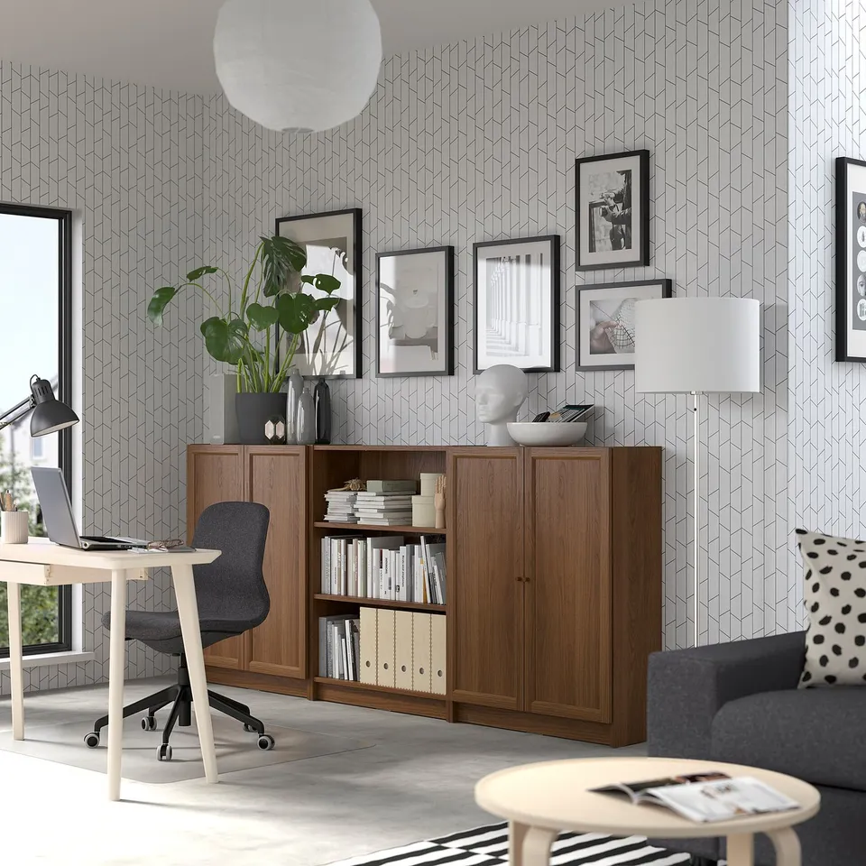 Modern living space with BILLY wooden sideboard, grey sofa, white office desk, and hanging frames.