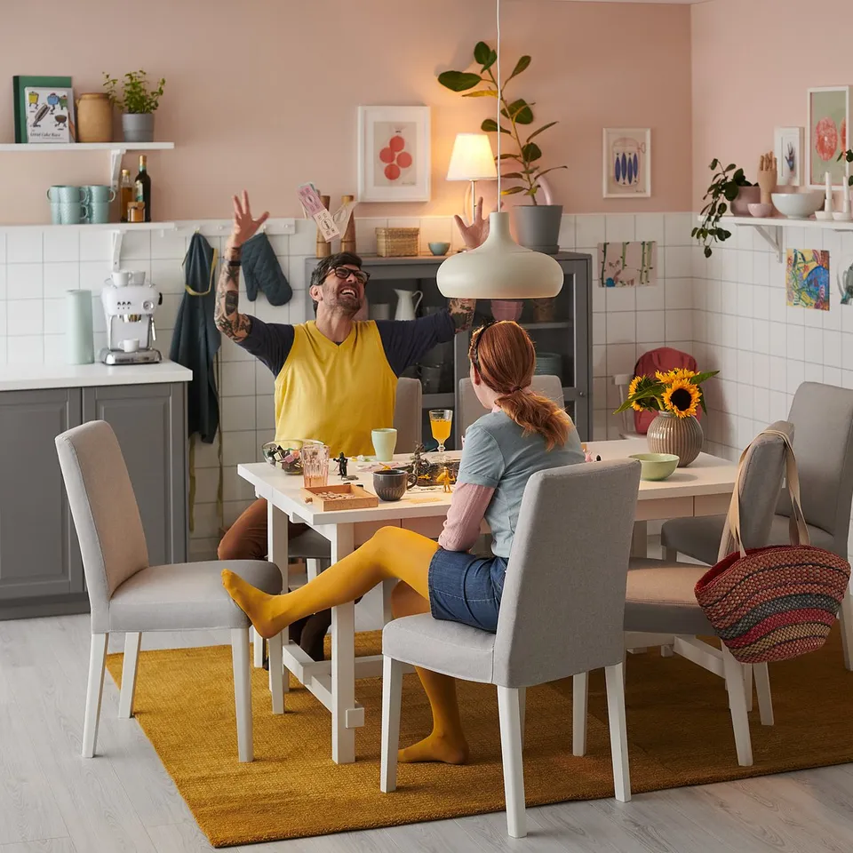 Family at white table with yellow & grey chairs in rustic kitchen.