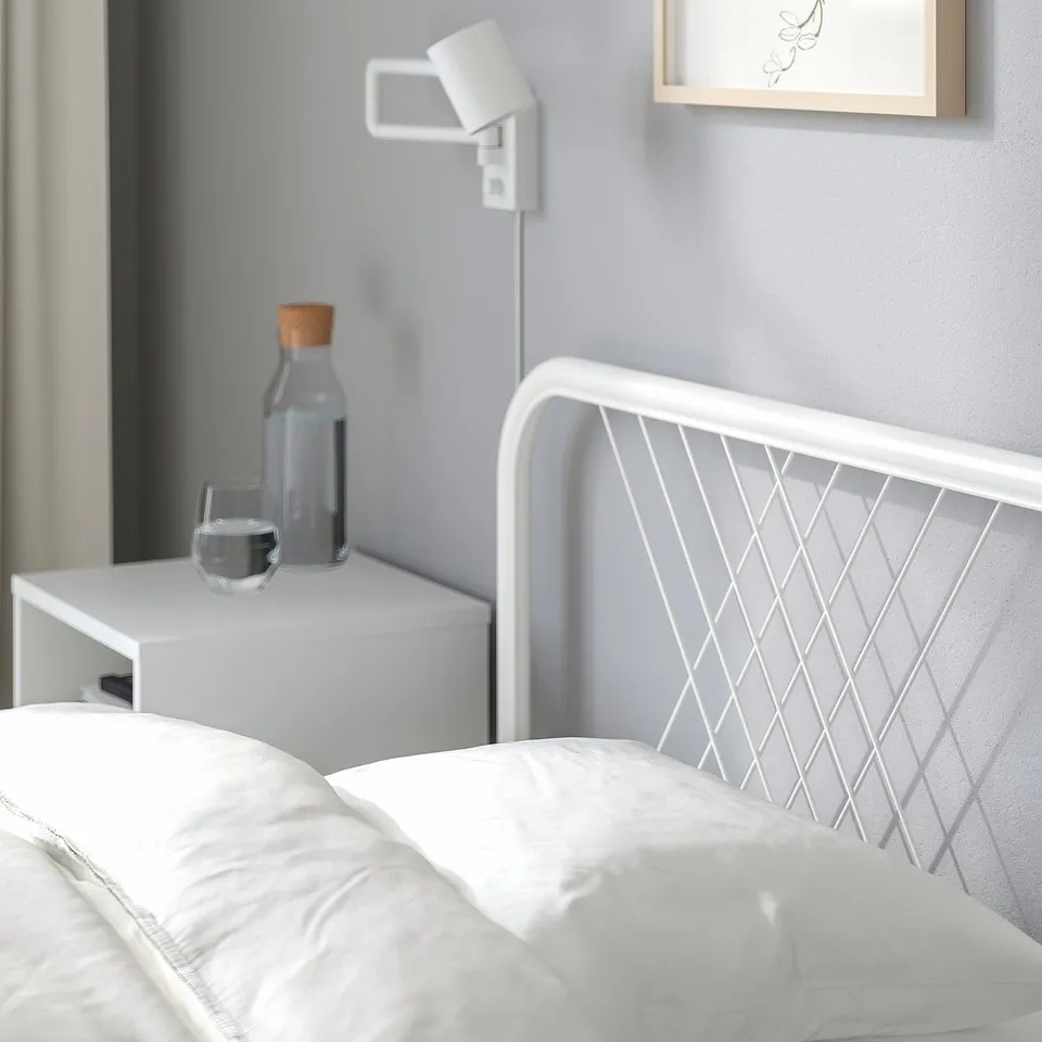 Modern bed frame with net headboard, bedside table, and wall light.