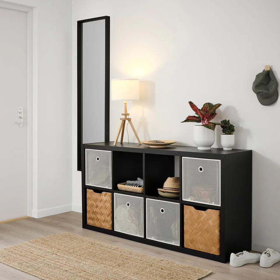 A DRÖNJÖNS white metal and wicker storage box for kallax shelving, featuring a mesh front and handles.