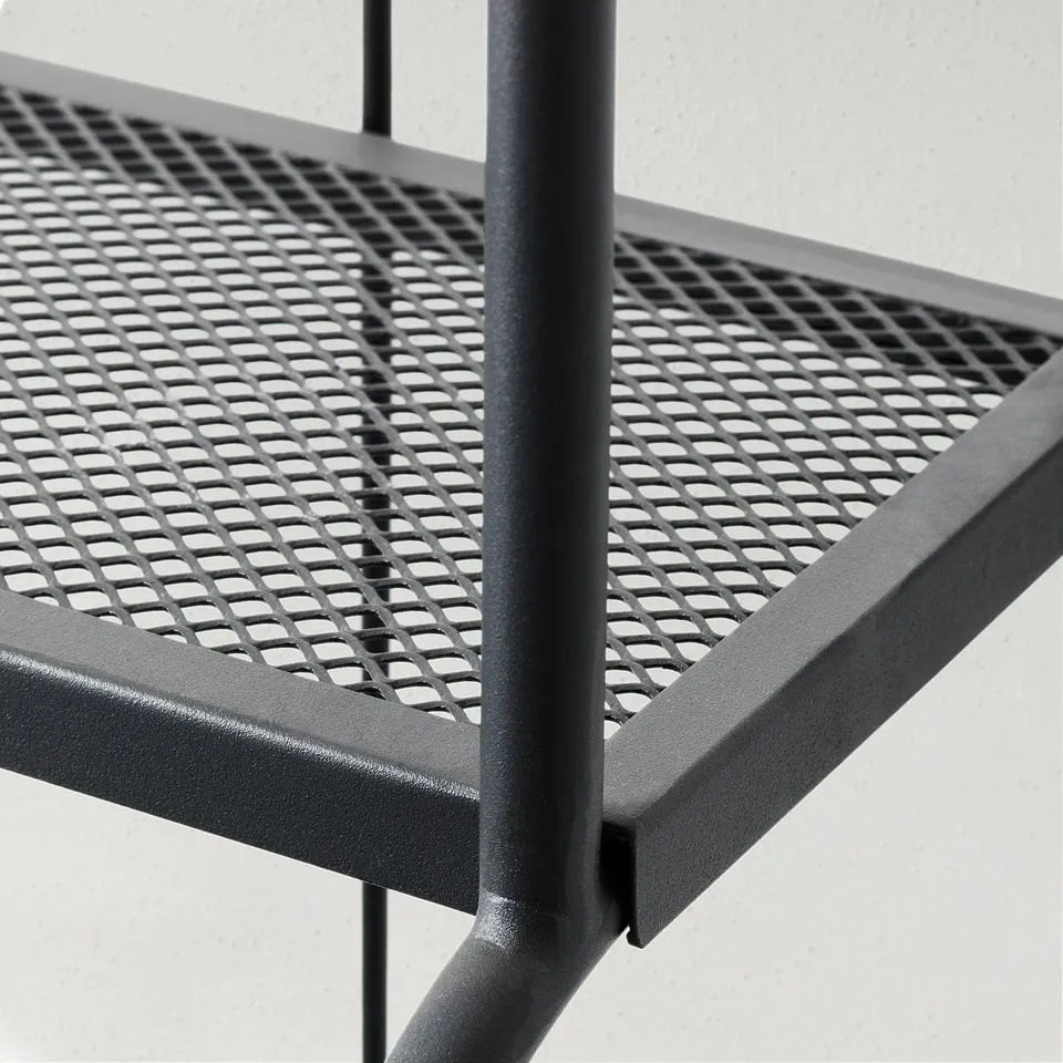 Close-up of black metal outdoor furniture with intricate perforated pattern, showing robust and adjustable design.