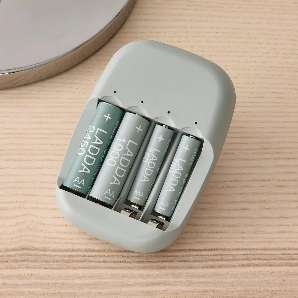 Four ladda rechargeable batteries in STENKOL charger; charging status indicated by led lights on light grey device.