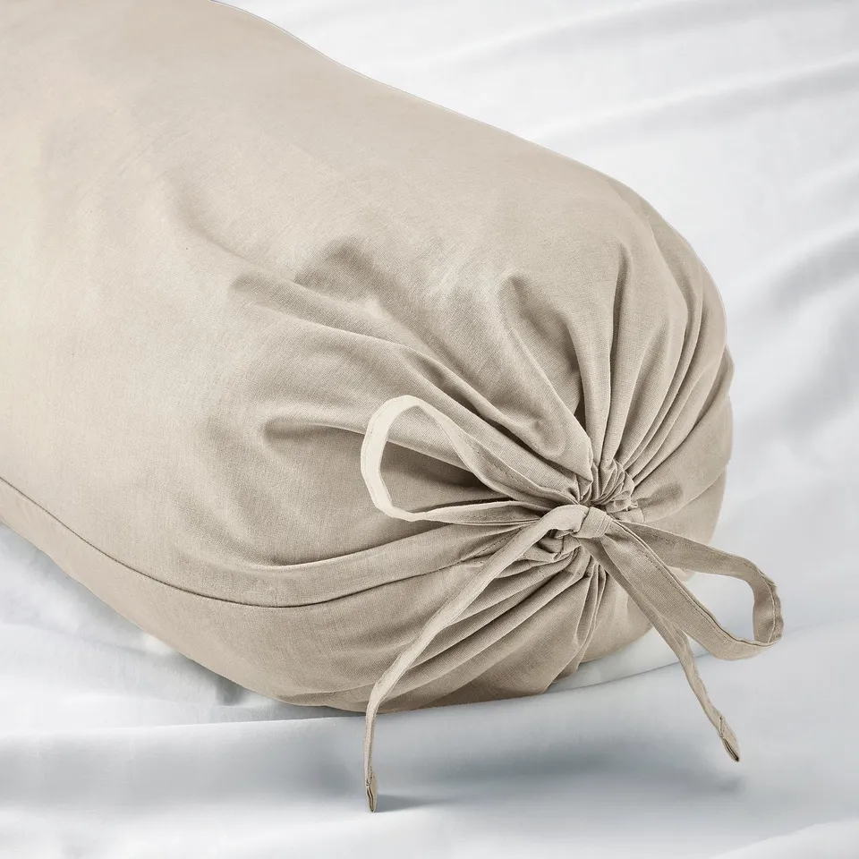 Cylindrical pillow with tied end, beige cloth, smooth texture, elegant design.