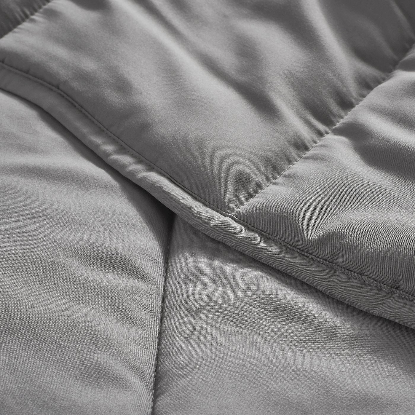 Close-up of a soft, grey comforter with smooth fabric and clean stitching.