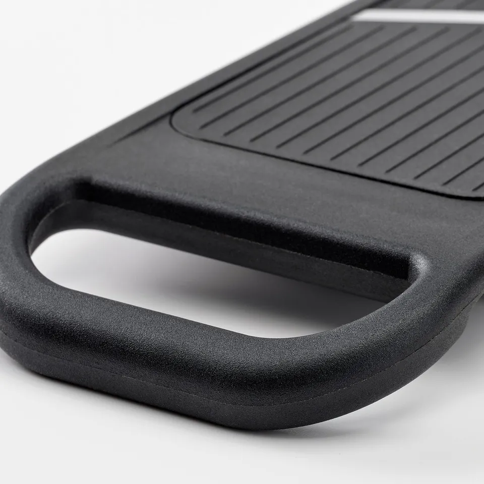 Black cutting board with handle and grooves for easy slicing.