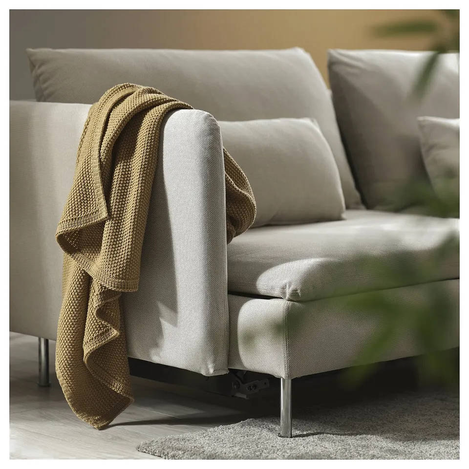 A light-colored SÖDERHAMN sofa bed with a beige blanket casually draped over the armrest.