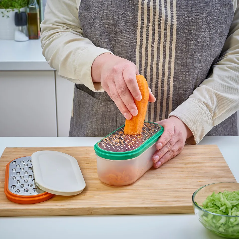 Person grates orange into UPPFYLLD container with lid.