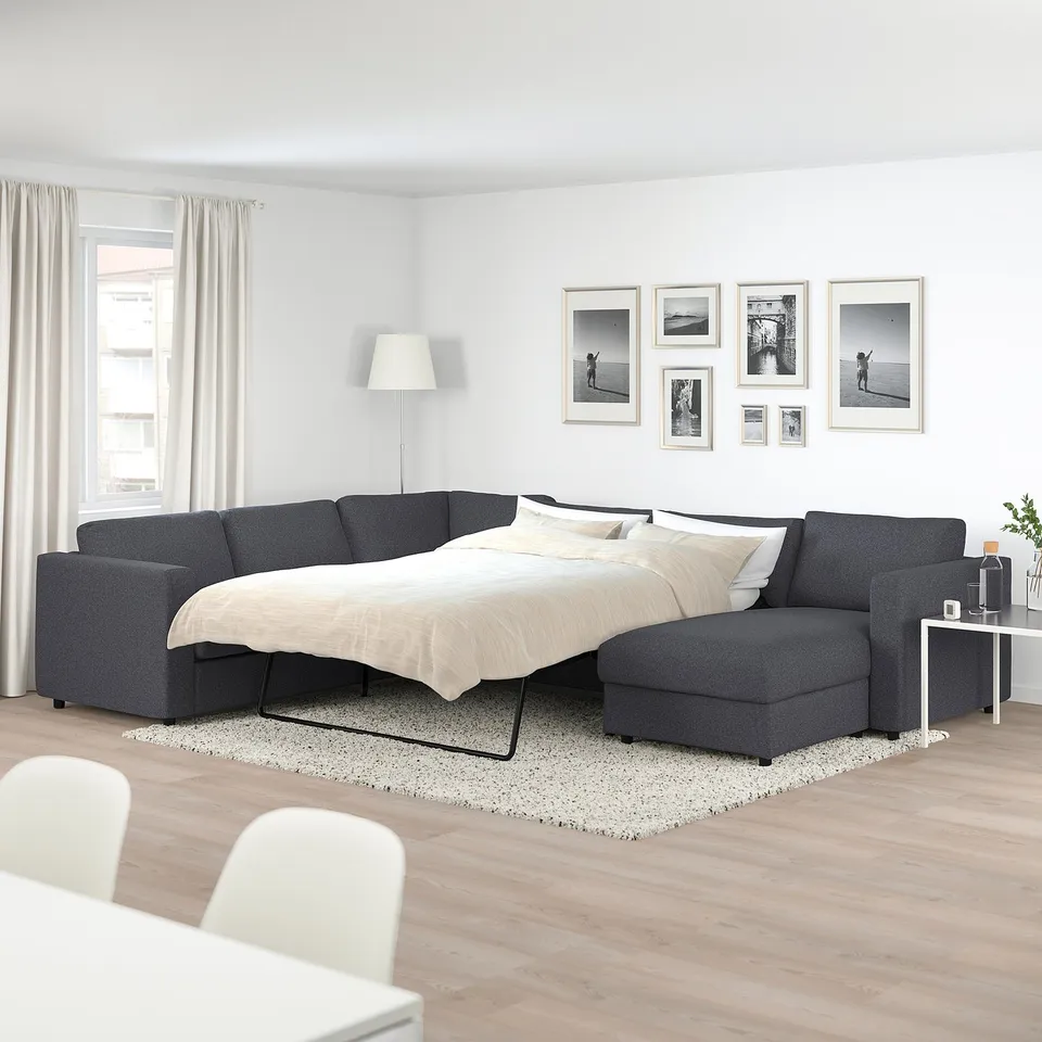 Modern grey VIMLE sofa-bed in minimalist room with large windows & art.