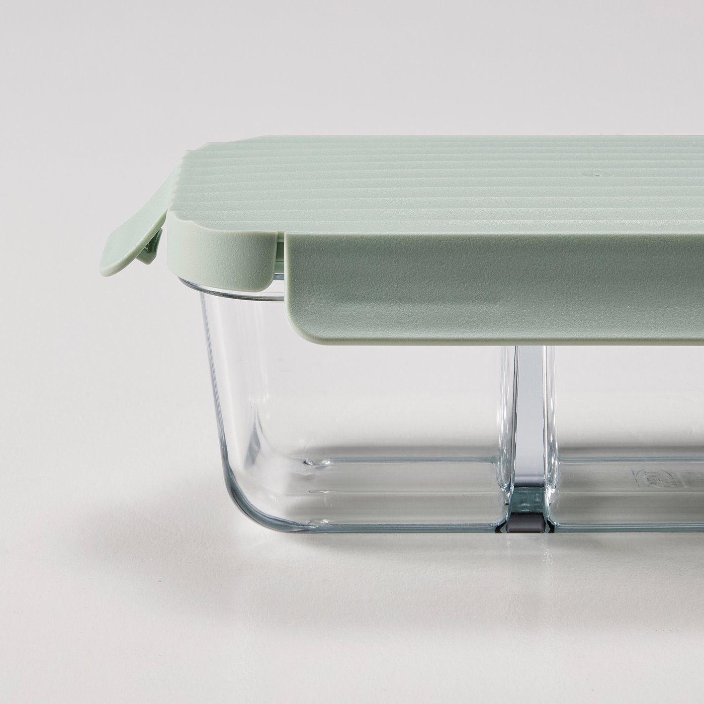 Glass lunch box with green lid, separated compartments for organised food storage.