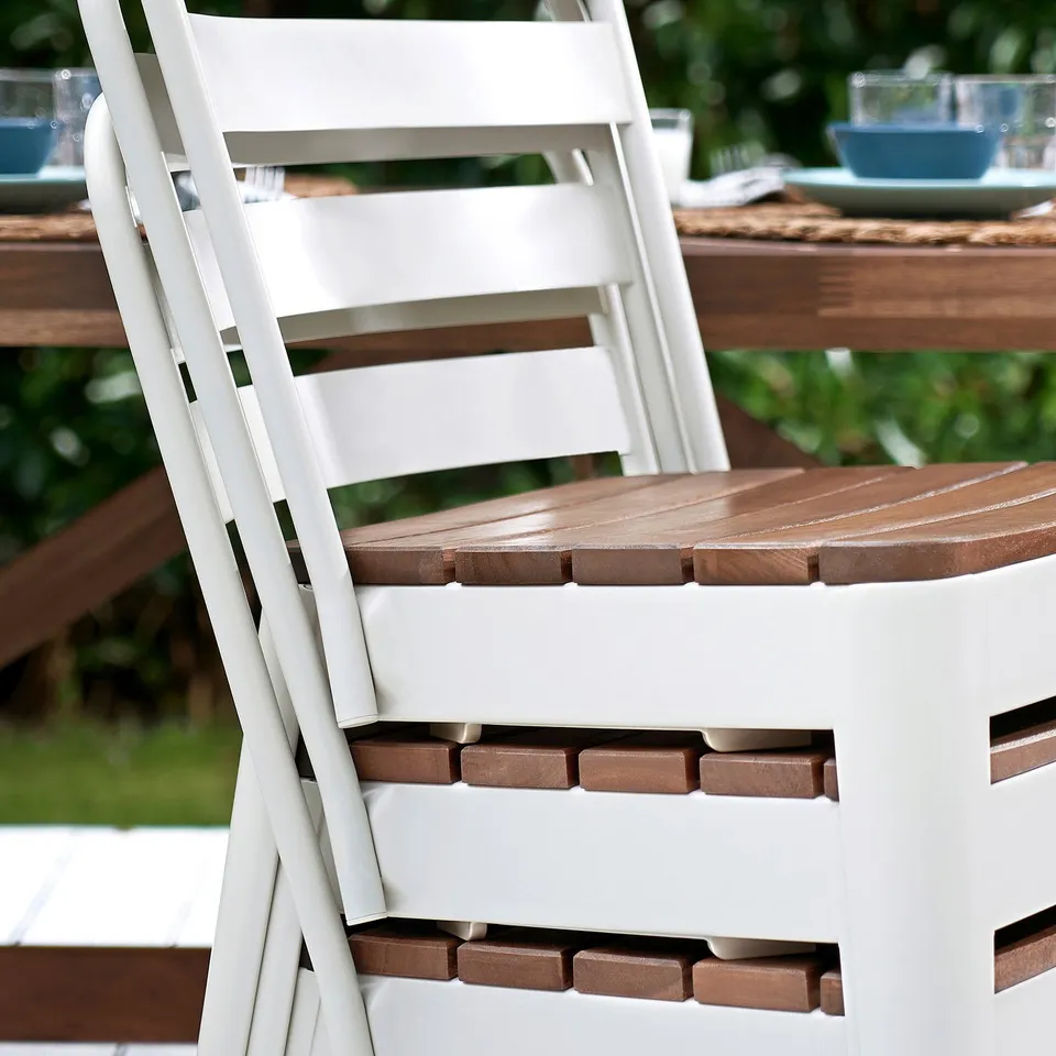White stacking chair, wooden seat. Part of NORRMANSÖ outdoor dining set.