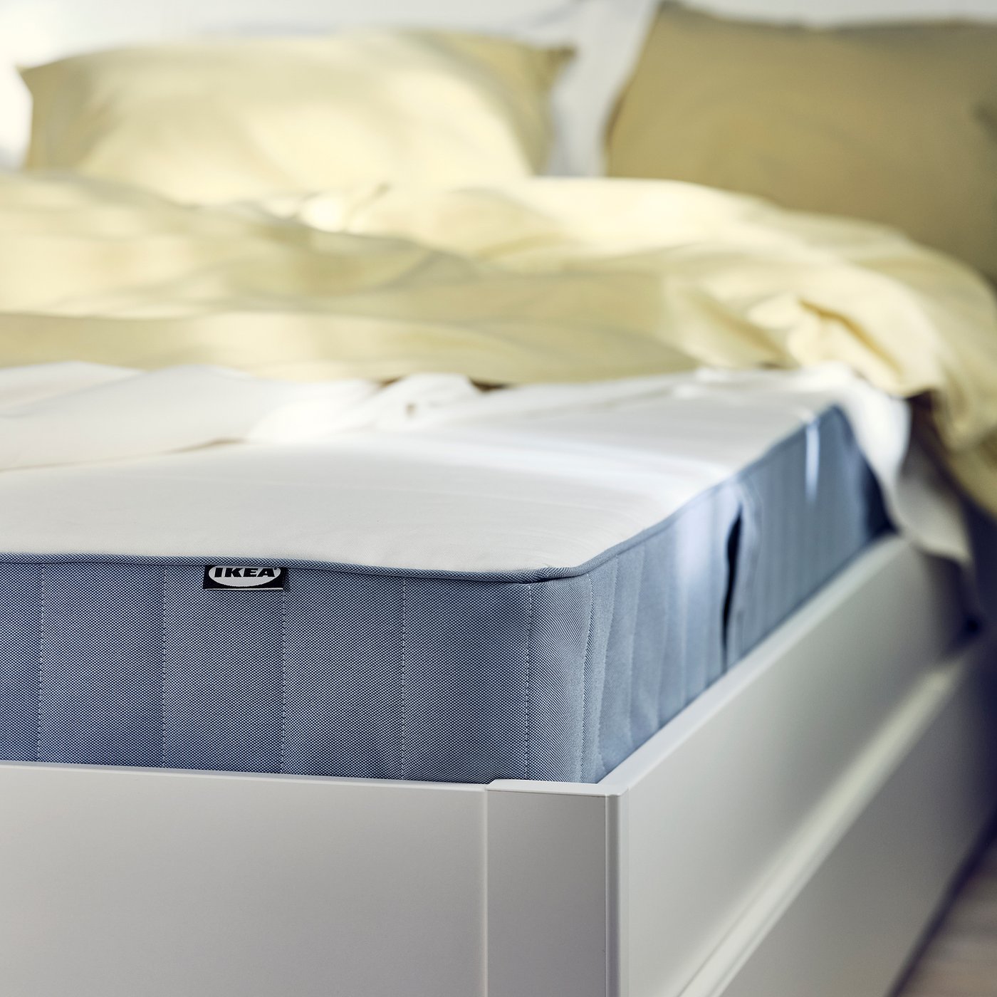 A close-up of an IKEA VESTMARKA mattress in light blue, featuring a textured surface and a white, simple design.