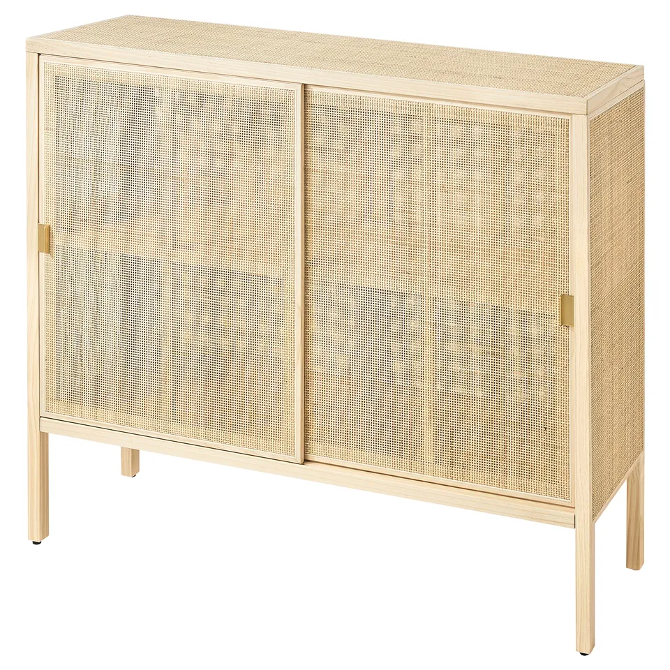STOCKHOLM 2025 rattan cabinet, light beige, rectangular with sliding doors, brass handles, natural wood legs, airy design.
