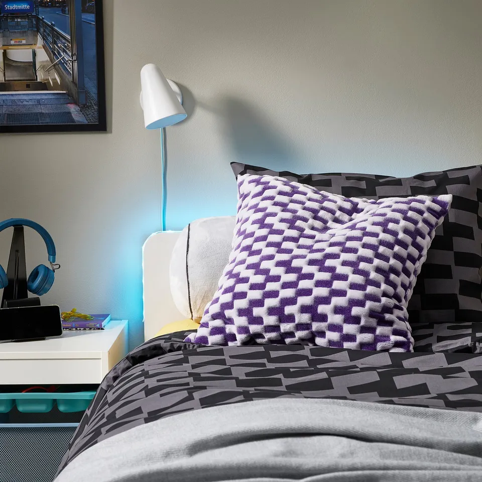 Teen bedroom with BLÅSKATA bedding, chequered pillow, turquoise lamp, and bedside essentials.
