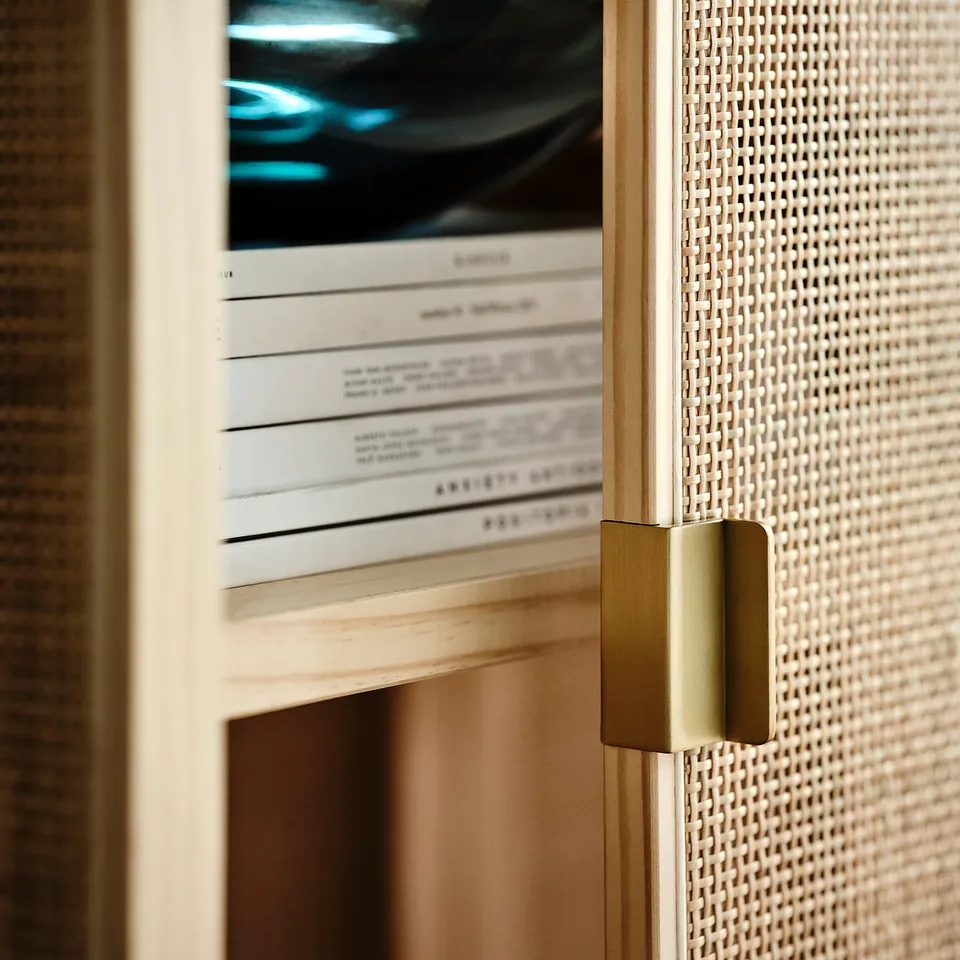 Modern cabinet with woven rattan, gold handles, showcasing sleek design and quality craftsmanship.