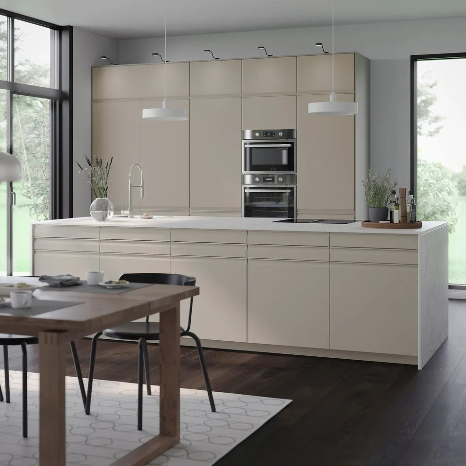 Modern kitchen with UPPLÖV matte beige cabinets, stainless steel appliances, and wooden table with black chairs.