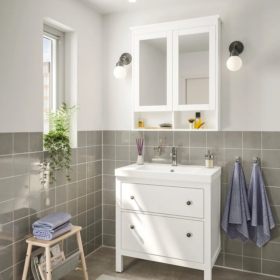 HEMNES white bathroom vanity with sink, drawers, & mirror cabinet. Wall lights & decor enhance modern look.
