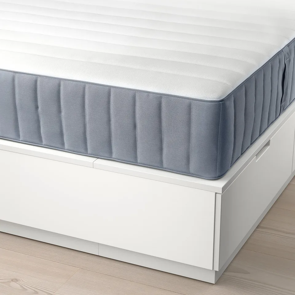 White bed frame with drawers, supporting grey mattress. Shows under-bed storage and smooth drawer function.