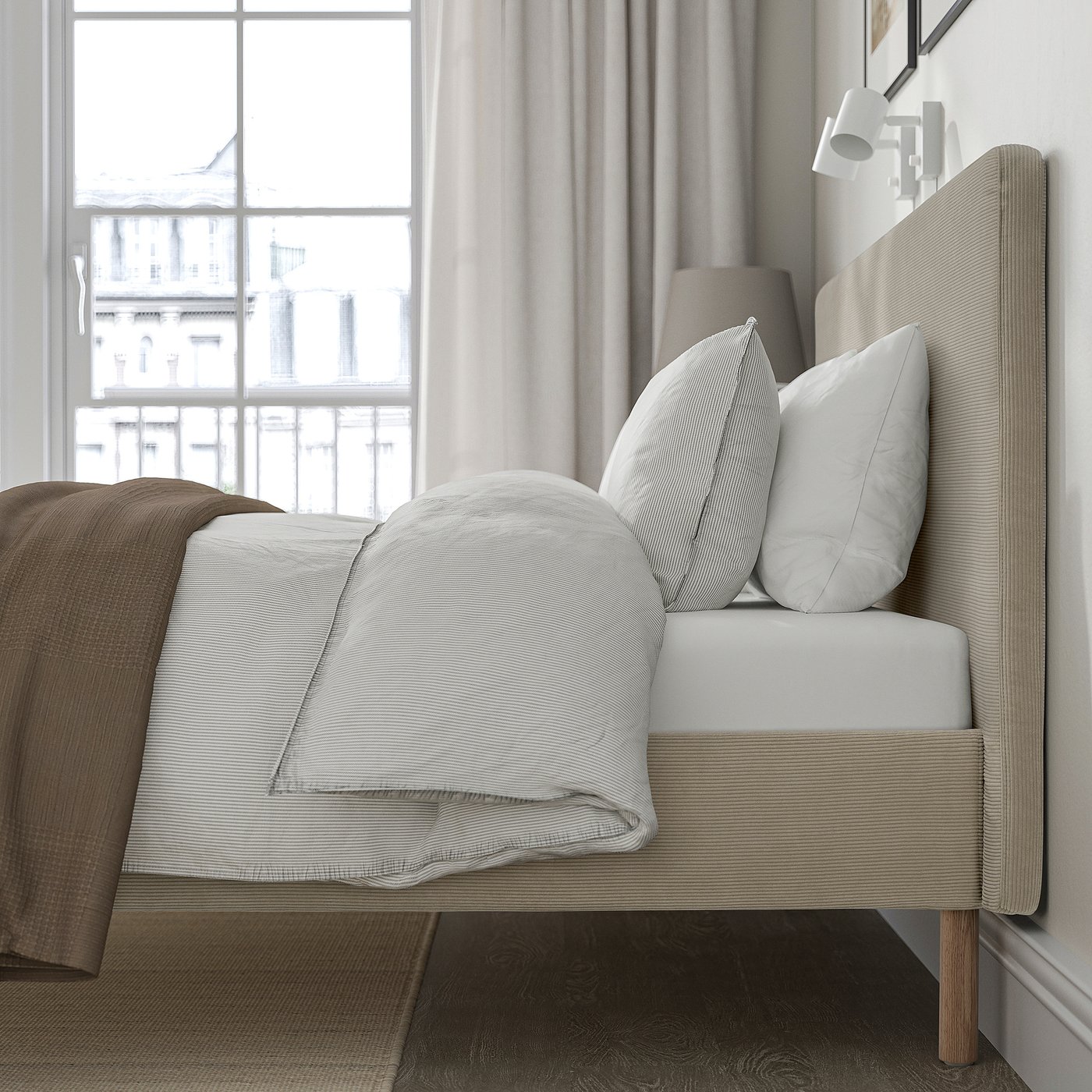 Bed with plush headboard, white bedding, light-colored cover, and large window with curtains.