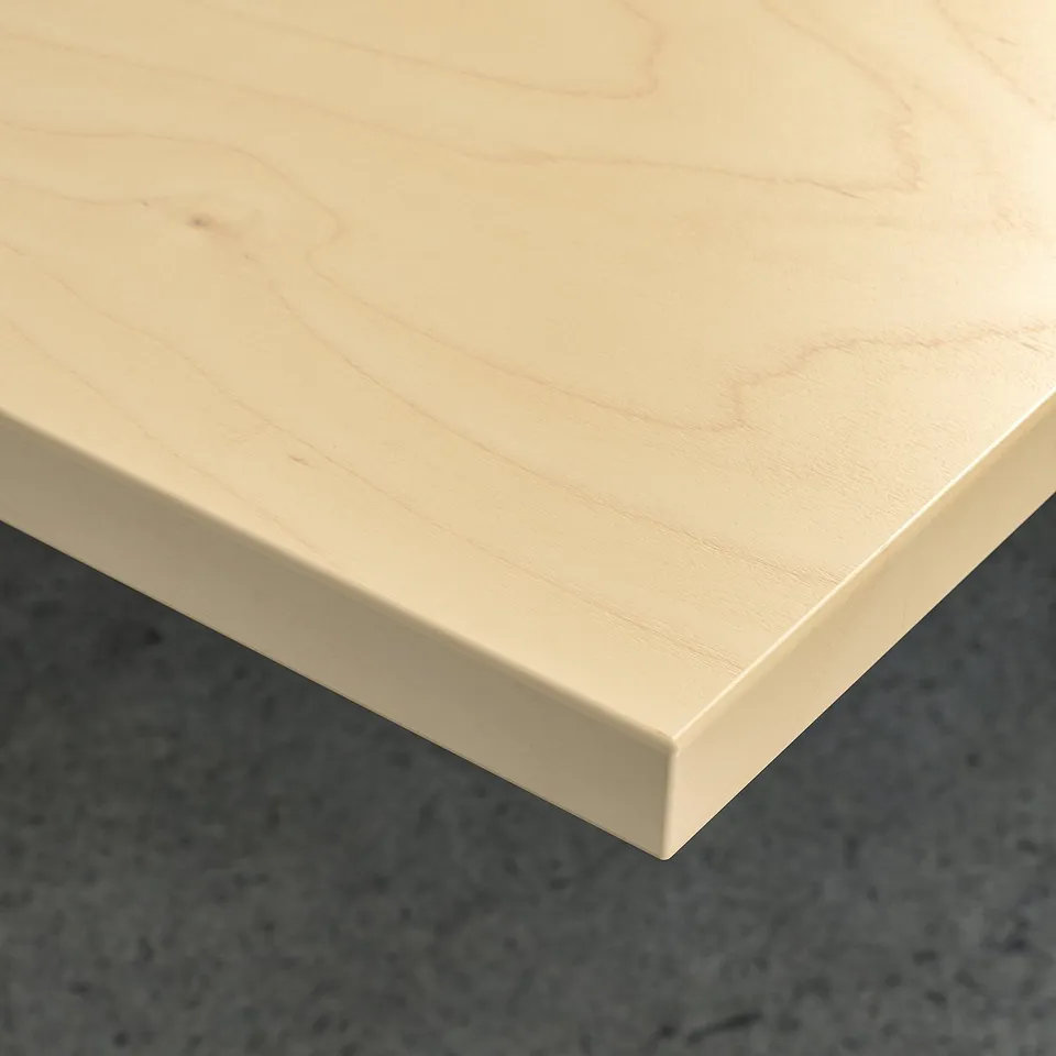 Close-up of light-colored wood desk; smooth, clean, and even surface indicating high quality.