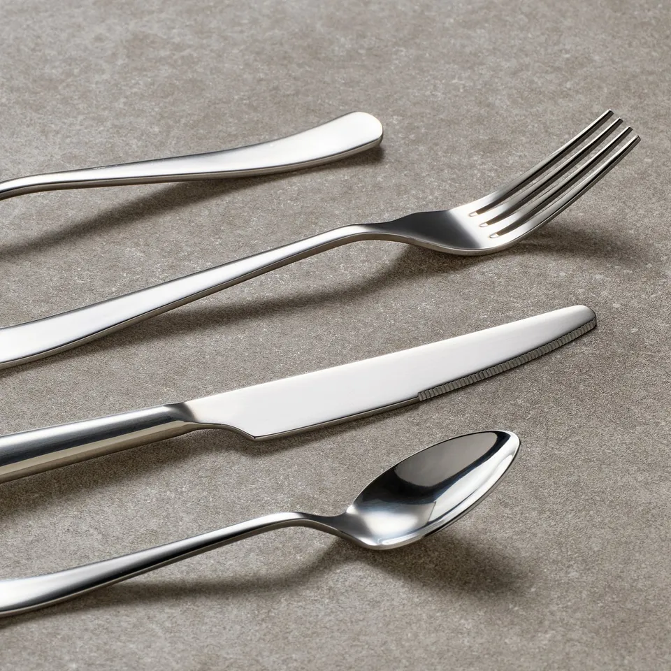 Stainless steel cutlery set: knife, fork, spoon on a textured surface showcasing sleek, durable design.