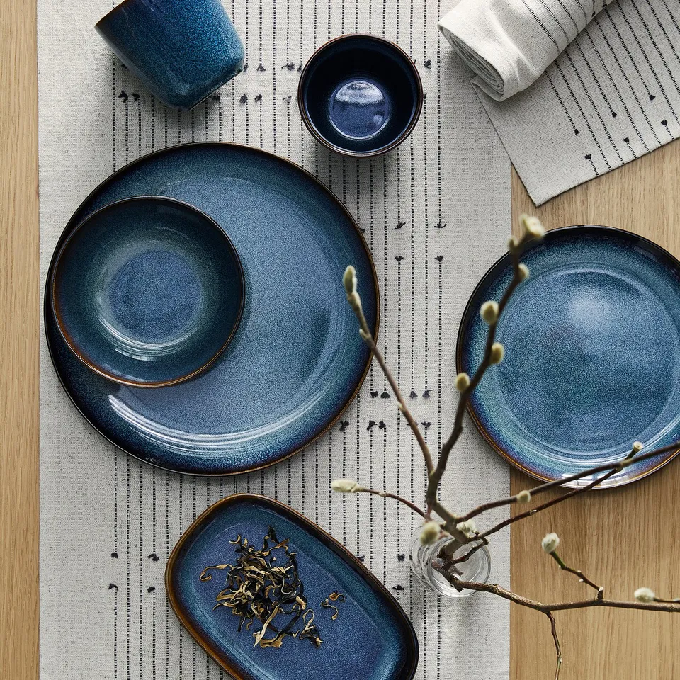 GLADELIG plates, ocean-blue with gold trim, displayed with mugs, bowls & decor.