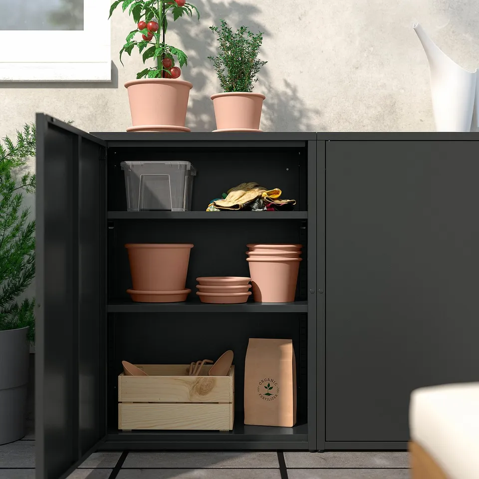 Black SUNDSÖ cabinet with pots, plants, and tools; perfect for balcony storage.
