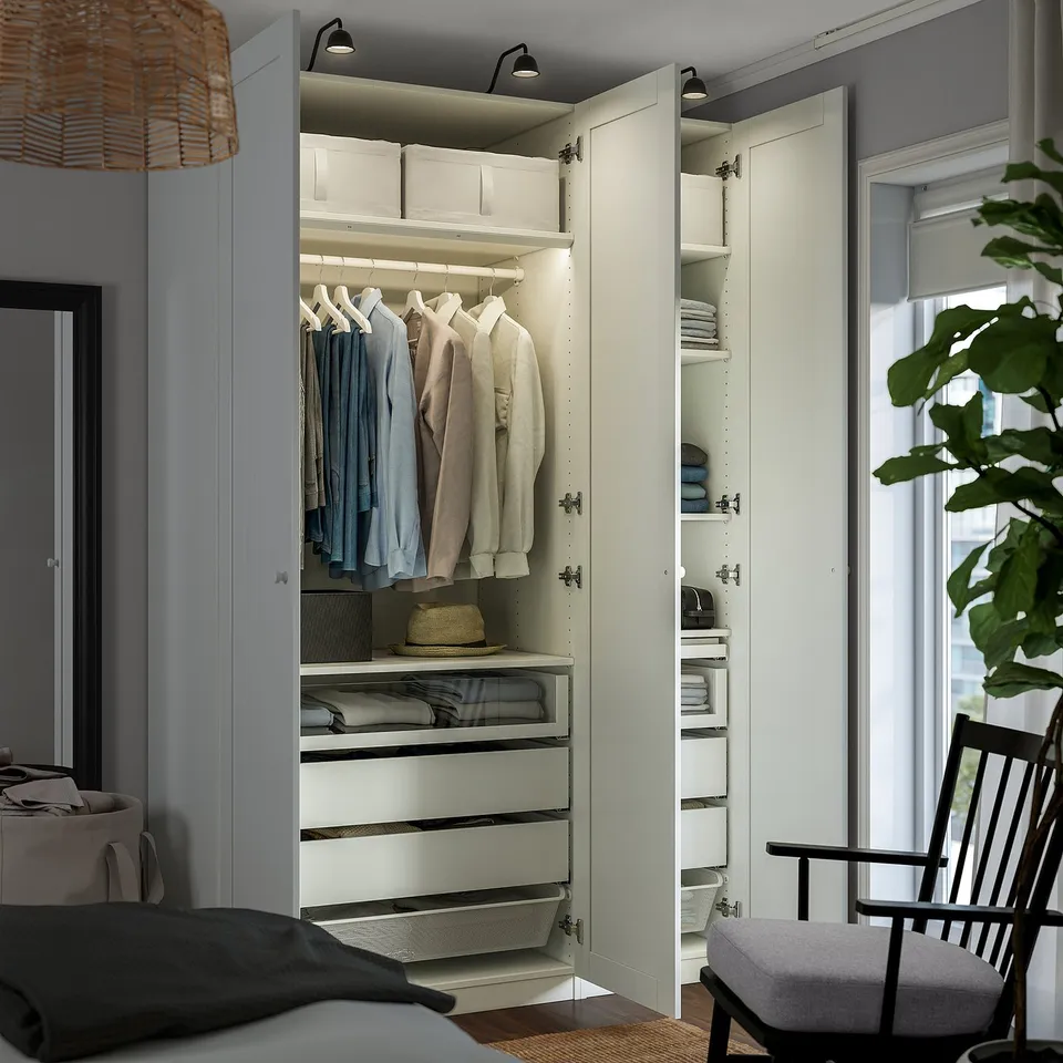 A wardrobe closet with clothes hangers, shelves, and drawers. It has built-in lighting and is fixed to the wall.