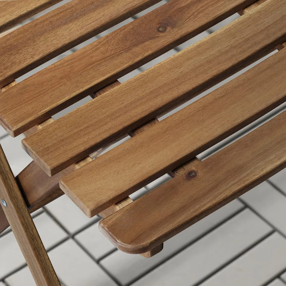 Wooden outdoor furniture close-up, showing smooth, durable acacia wood slats and sturdy metal fastenings. Ideal for patio use.