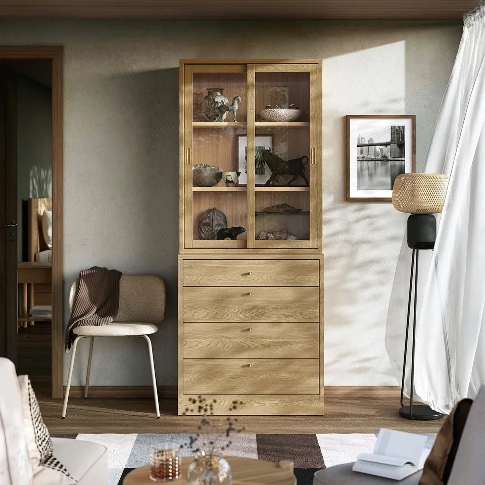 Modern living room with wooden cabinet, grey chair, and tall lamp.