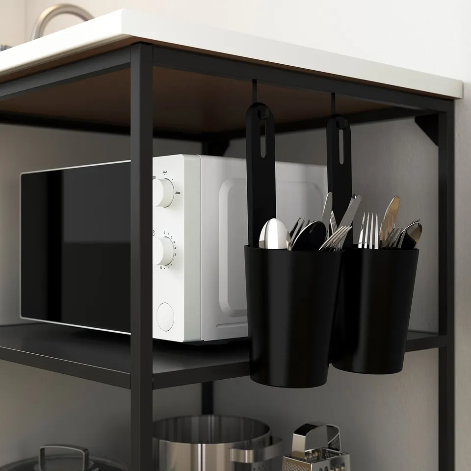 Kitchen shelf with a microwave and hanging utensil holders.
