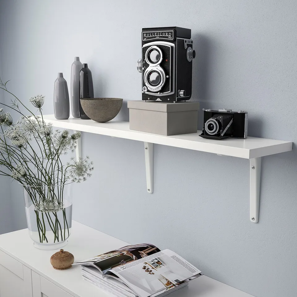 White wall shelf with vases, cameras, and a flower vase displaying decorative items.