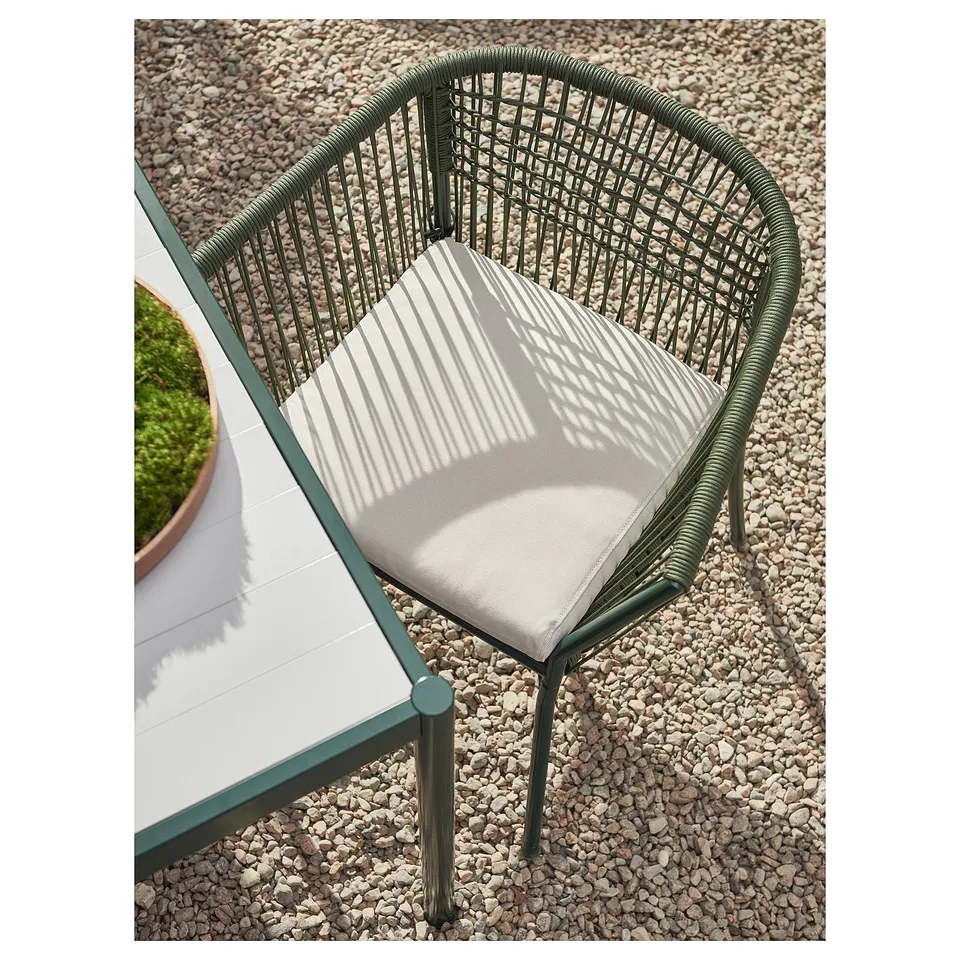 Modern outdoor chair, teal frame, white striped cushion, woven design, gravel background.