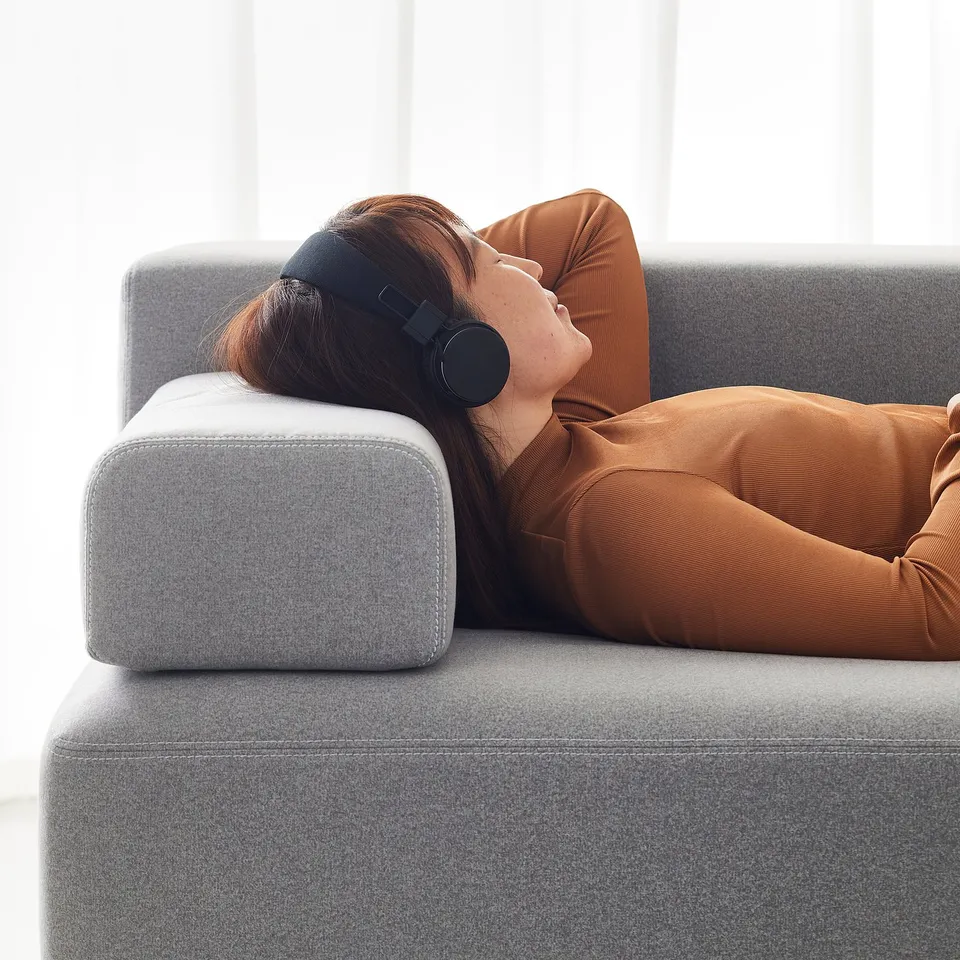 Person relaxes on JÄTTEBO sofa with headphones, enjoying music and comfort.