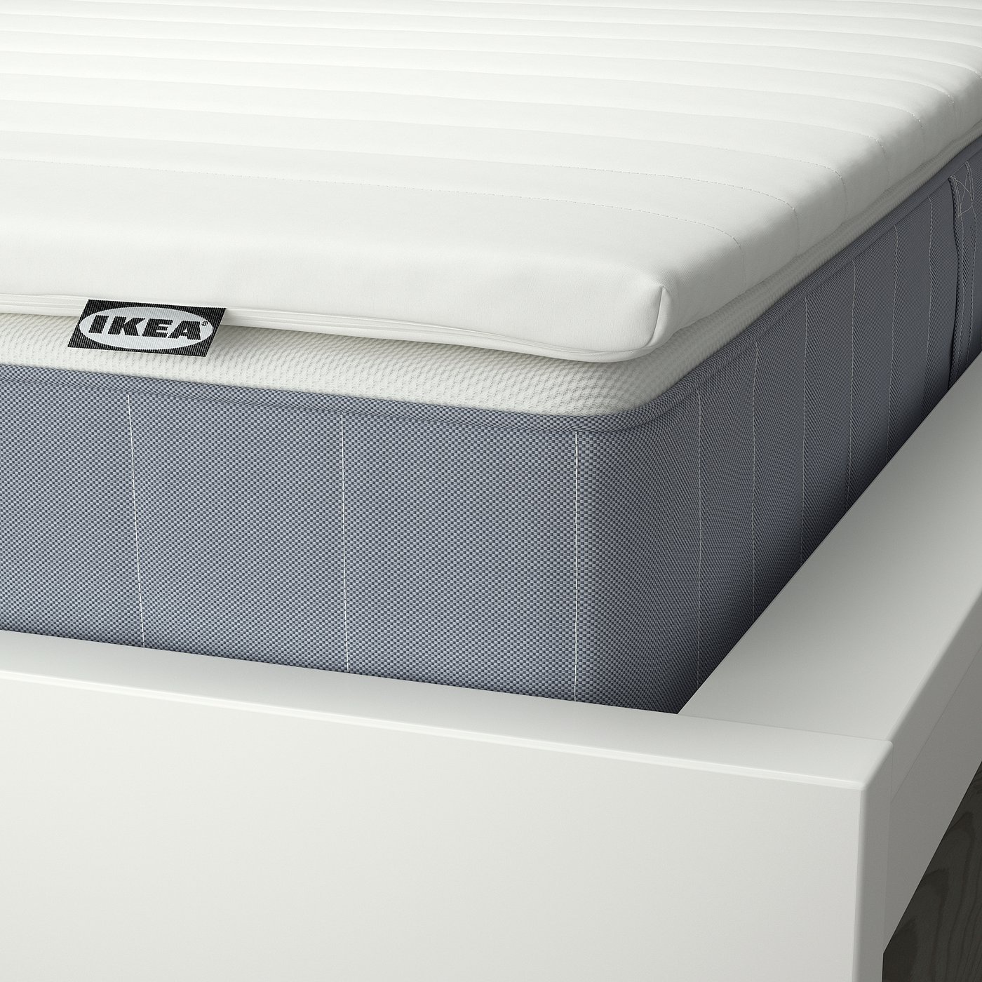 Close-up of IKEA mattress showcasing quality: white quilted top, grey base, and visible branding.