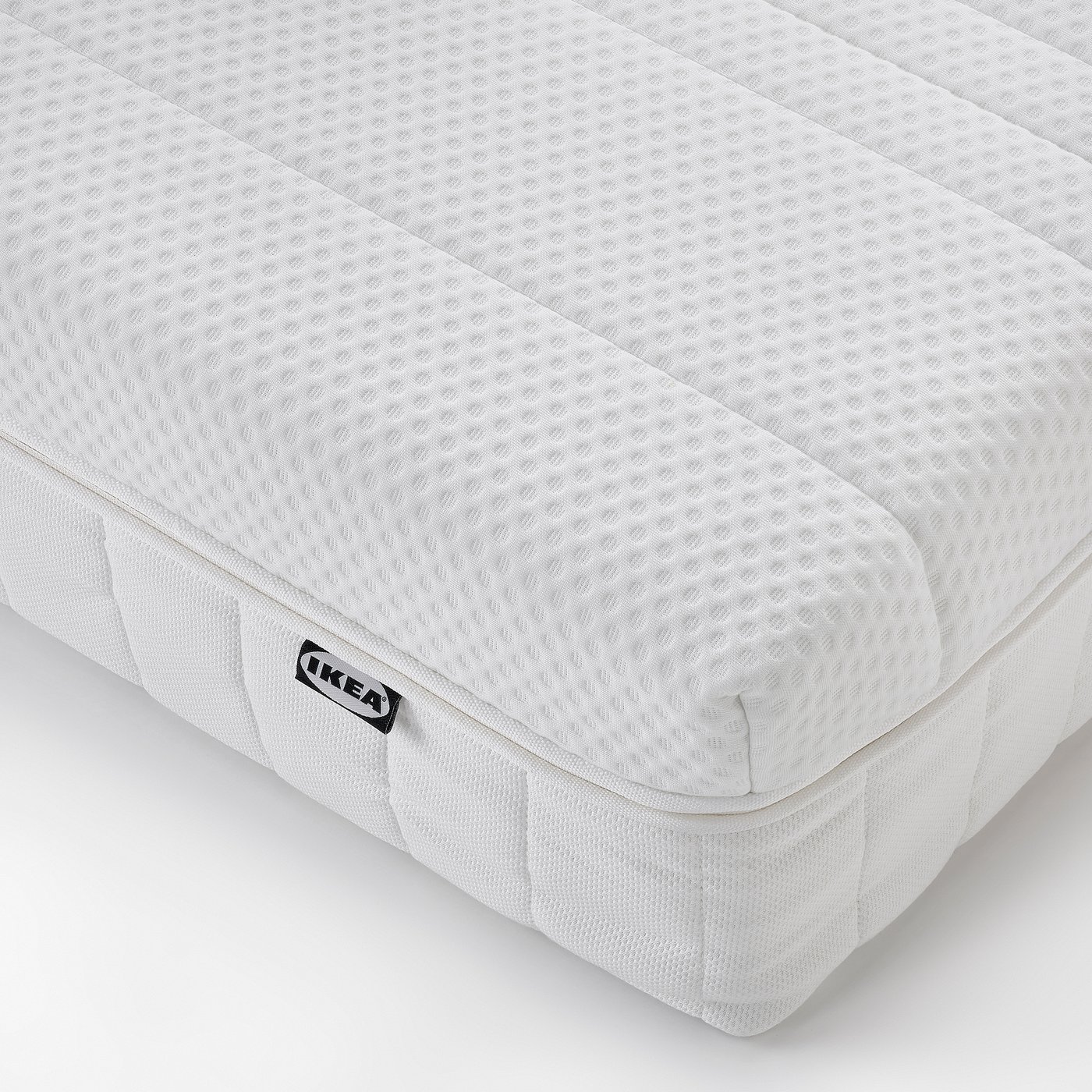 White mattress corner, IKEA logo visible, textured fabric, firm design.