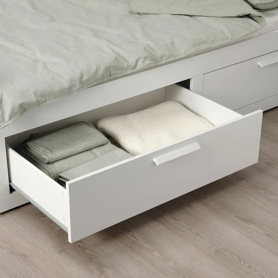 Bed with open drawer. Drawer holds folded blankets and towels.