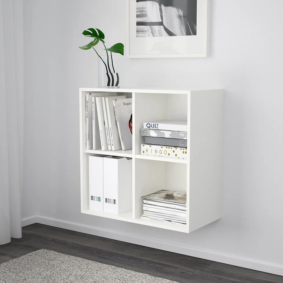 White wall-mounted shelf unit with three compartments storing books and games.