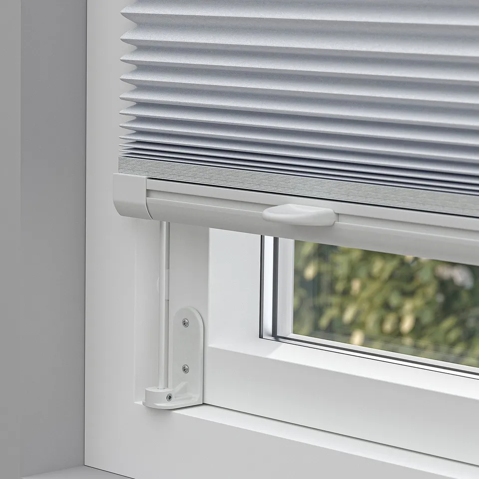 Window blind with top handle pulled down, blocking light. Mounted with adhesive brackets.