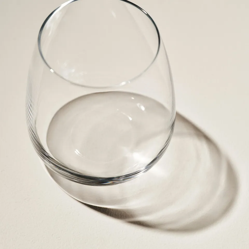 Glass on surface, clear, reflective, shadow below.