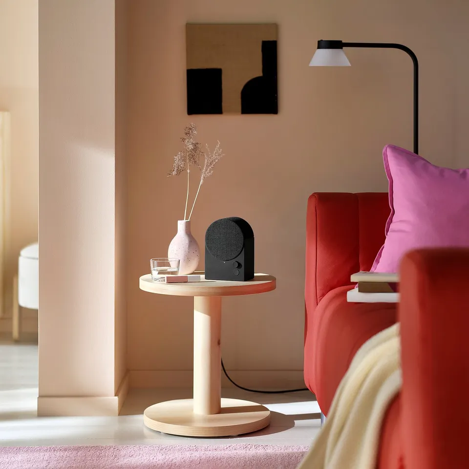 Modern living space with red chair, wood table, and sleek black speaker.