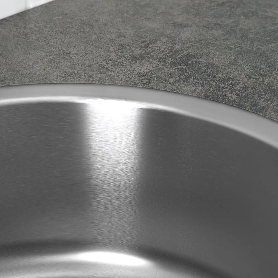 Stainless steel sink close-up, polished finish reflecting light, set on granite countertop.