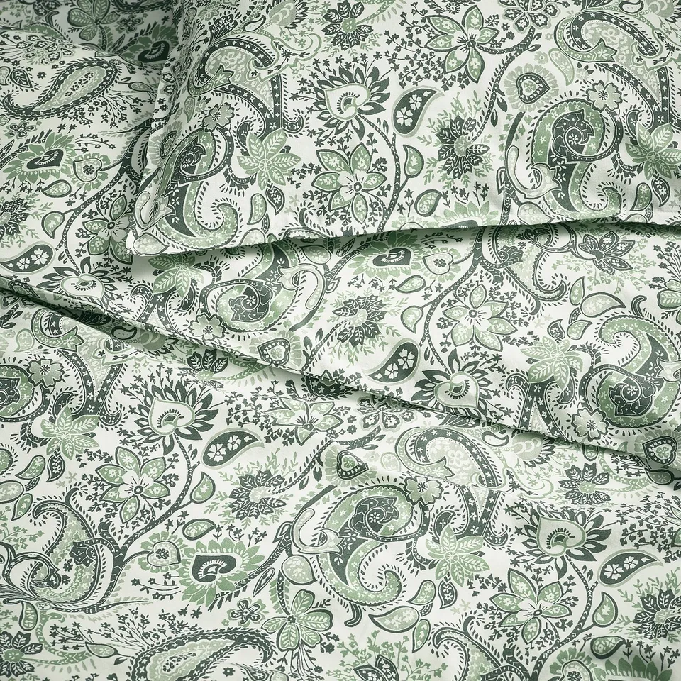 Paisley-patterned bedding with intricate green designs on a white background, showcasing high-quality fabric and detailed craftsmanship.