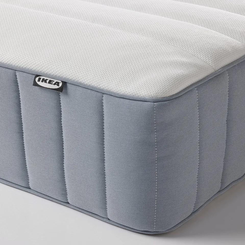 Close-up of a firm mattress with grey fabric and white top, showcasing quality design and brand label.