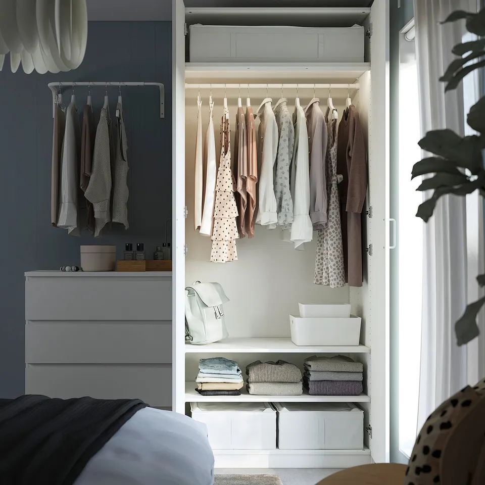 Closed wardrobe displaying clothes, shelves, and storage boxes, with lighting inside.