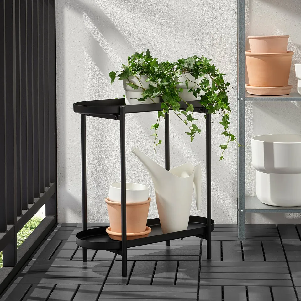 Small indoor/outdoor plant stand with two shelves. Holds pots and watering tools, doubling as a side table.