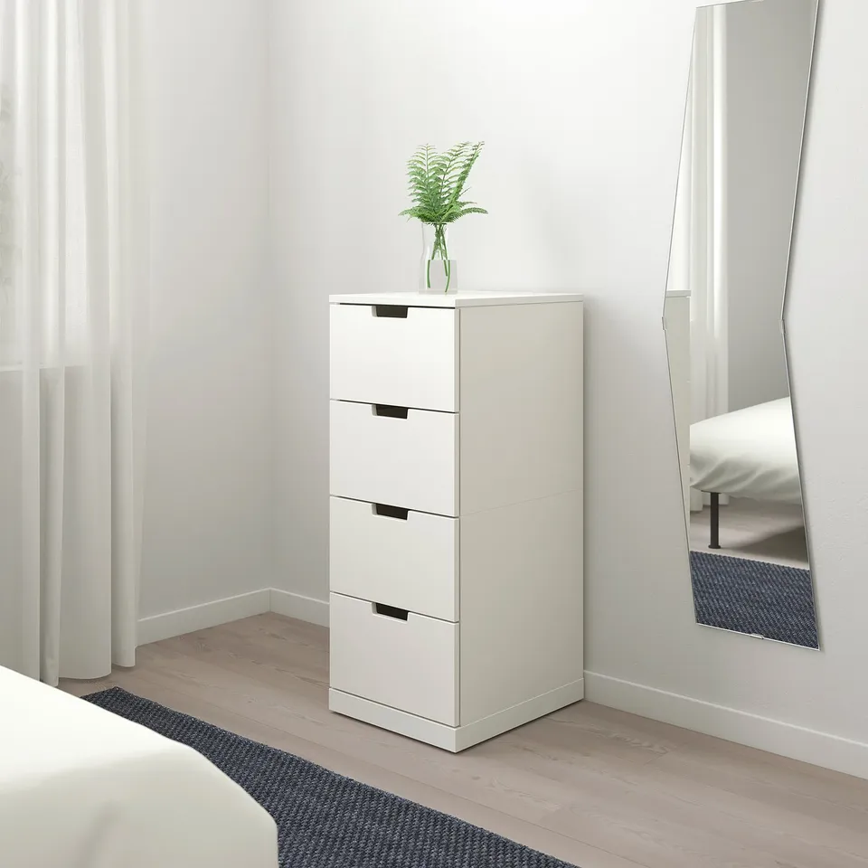 Minimalist white NORDLI chest with 4 drawers, black handles, plant, mirror.